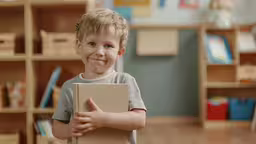 a small child holds a book in his hands and gives the thumbs up,a young boy is holding up a book in a library