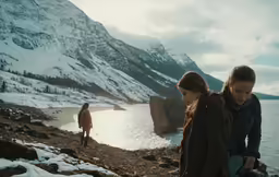 a group of people standing around with a mountain behind them