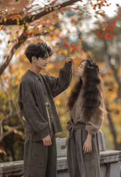 a couple is standing outside in the fall,two people standing together holding each other hands and looking at each other