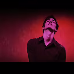 a man in black shirt with red lighting on back ground