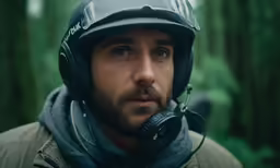 the man wearing the motorcycle helmet stands in the woods