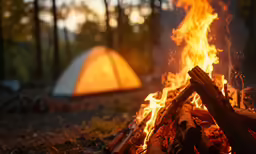 bonfire with tents in the background with wood