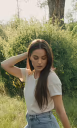a woman in jeans stands outdoors near trees