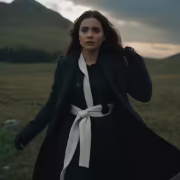 a woman in the middle of a field looking out at the sky