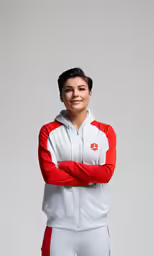 the woman in white and red tracksuit stands with her arms crossed