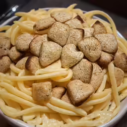a white bowl filled with lots of pasta and heart shaped meat