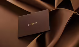 a card with the word sister is shown in gold lettering on top of a brown fabric