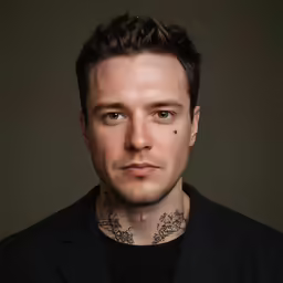 a male in a black shirt and neck tattoo