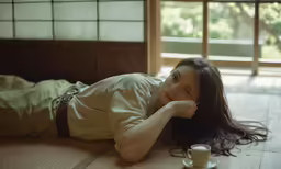there is a woman laying on the floor and drinking tea