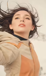 woman in brown jacket and white top is shown