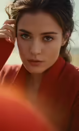 a woman wearing red shirt leaning on a wall