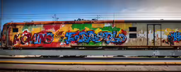 train with colorful graffiti on the side of it,a train car that has spray paint all over it