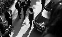 a black and white photo of men in suits on a street