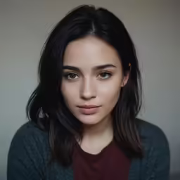 young woman with black hair wearing a green cardigan