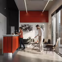 two people in the center of a living room with an orange counter