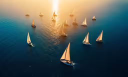 a bunch of boats floating in the ocean during sunset