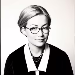 a woman with glasses poses for a black and white photo