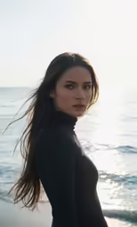 a woman in wetsuit standing on the beach near ocean