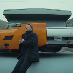 a man standing on top of a parking lot next to an orange truck