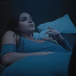 a person in the bed with a remote control