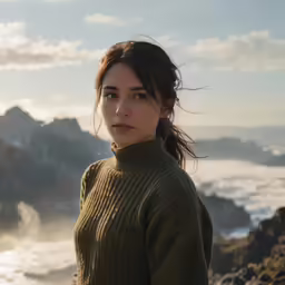 a young woman stands overlooking the sea from cliffs