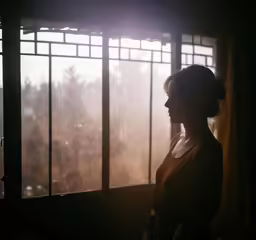 a woman standing in front of a window with sun streaming through