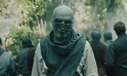 a man wearing a large mask standing next to a group of other people