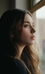 a woman looking out the window as she stands and stares