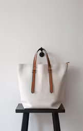 a white bag sitting on a wooden stool