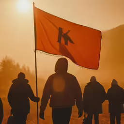 a man holding a red and yellow flag while walking down a road