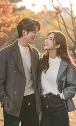 an asian couple walking in the leaves of a tree,a beautiful young woman and a man standing next to each other