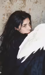 a woman sitting with a bird on her shoulder