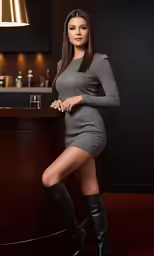 a woman in a short grey dress posing with black boots
