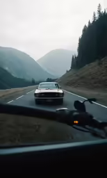 a white car driving down a road through a mountainous valley