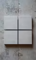 four square pieces of white tile sit on the ground