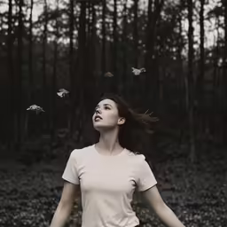 a woman in a white shirt standing in a forest surrounded by moths