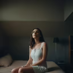 a young woman sitting on top of a bed in a bedroom