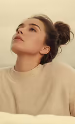 a woman laying on a white sheet looking up with her eyes closed