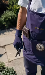 a man with tools attached to his back wearing purple overalls and white shirt
