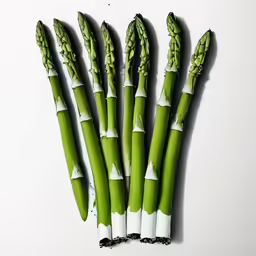 five green asparagus cut in half and laying on a table
