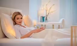 a woman laying in bed with her hands on a pillow