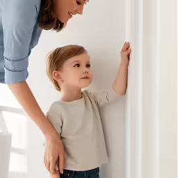 a little girl with her hand on the wall