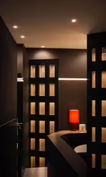 an empty room with large black doors and a red lamp