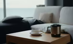 the table is in front of the sofa and has a coffee pot on top