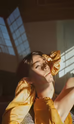 a woman in a yellow dress posing in a sunlit room