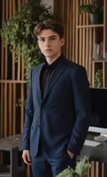 a man in a suit is standing by some plants