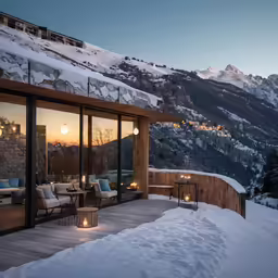 the sun sets in the mountains beyond a modern house