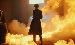 a lady in a long dress standing on a fire