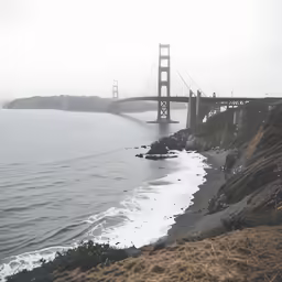 the golden gate bridge is overcast, and fog covers the coastline and shore