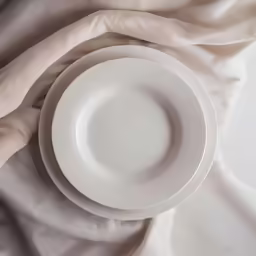 an empty plate sitting on a white table cloth